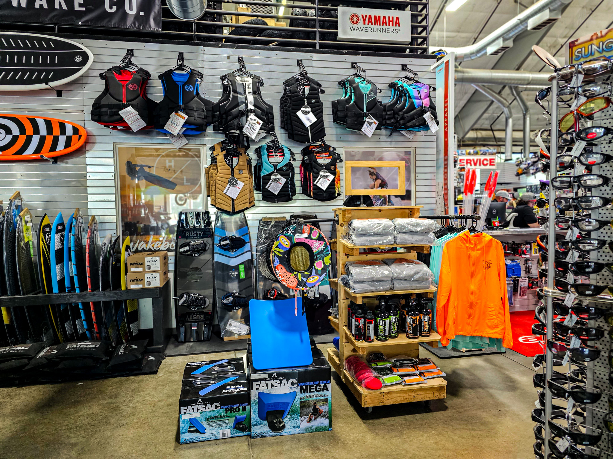 Wall of boating accessories including life jackets, wake boards, surf boards, sunglasses, fatsac …